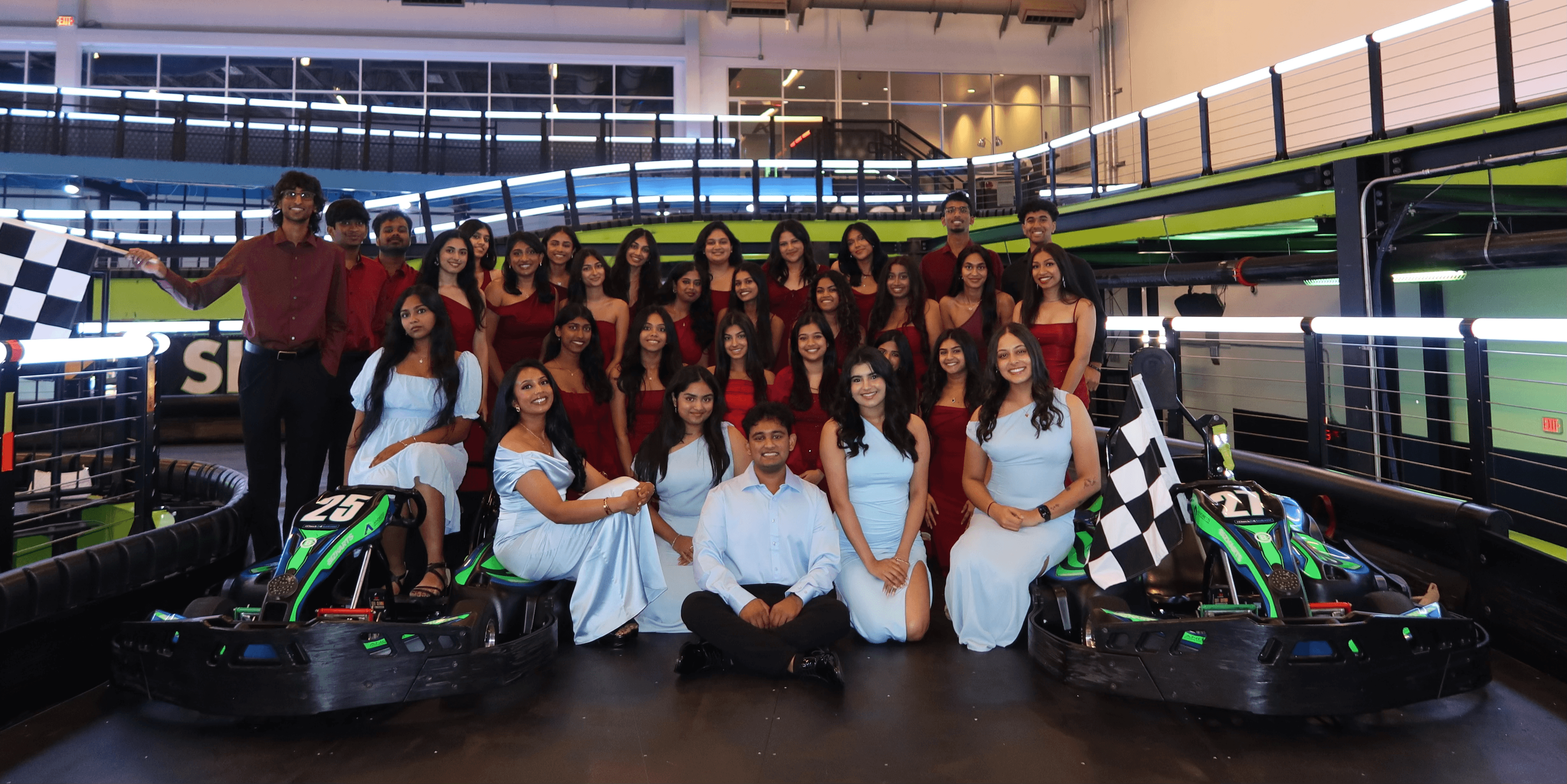Awaazein Exec Board 2026 holding checkered flags at an indoor kart track